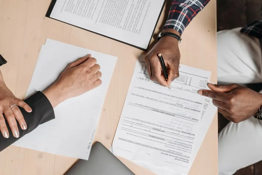 Pessoas preenchendo documentos sobre a mesa