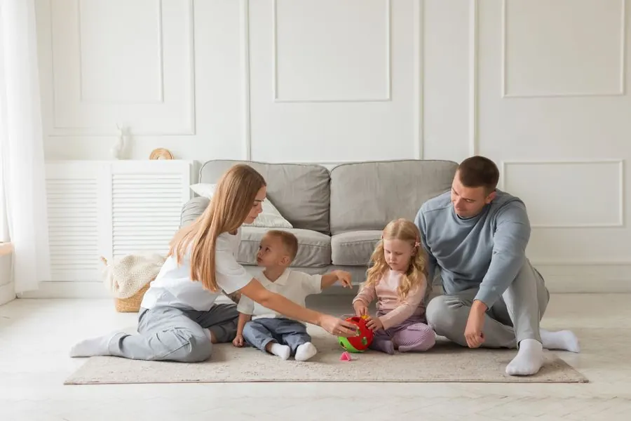 Pais brincando com os filhos em uma sala ampla